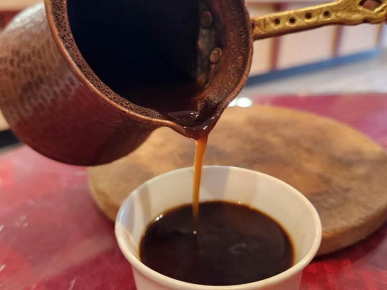 Traditional Lebanese coffee being poured from a brass pot into a small cup at That Lebanese Place.