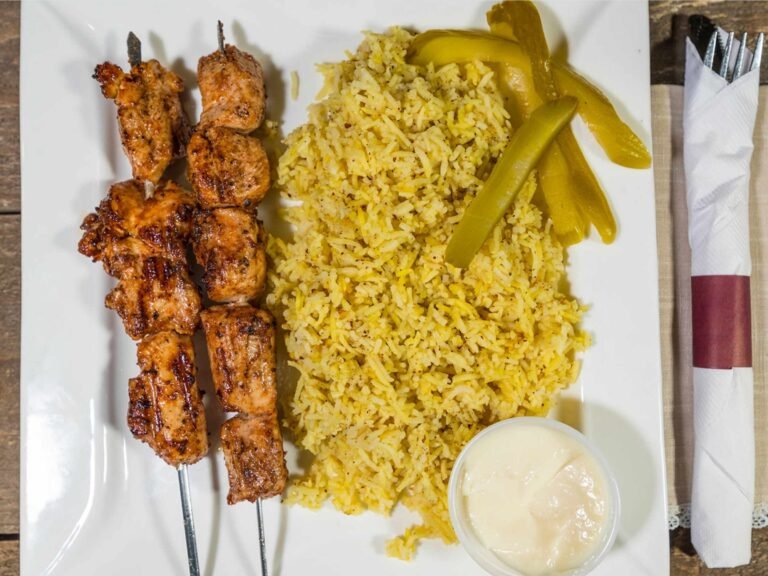 Lebanese entrée plate from That Lebanese Place featuring grilled chicken kebabs, basmati rice, pickles, and garlic sauce.
