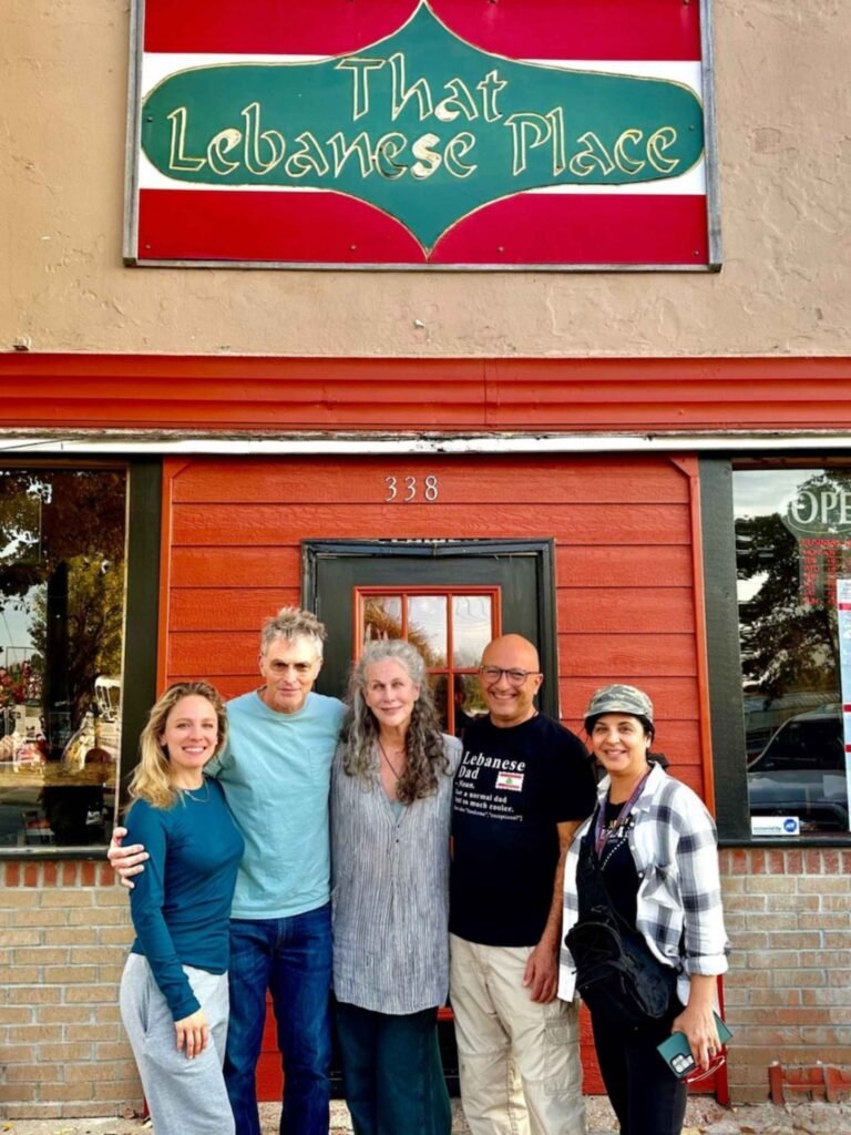 Chef Elie Ghanem standing with guests in front of That Lebanese Place restaurant, sharing smiles and Lebanese hospitality.