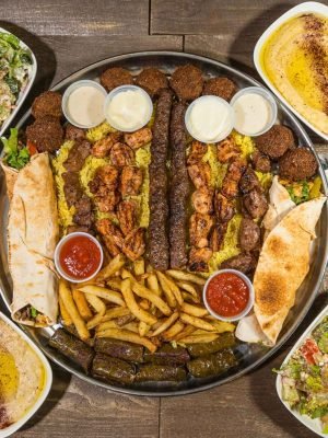 The Family Tray from That Lebanese Place featuring grilled meats, falafel, hummus, rice, fries, grape leaves, pita, and fresh salads — a Lebanese feast made to share.